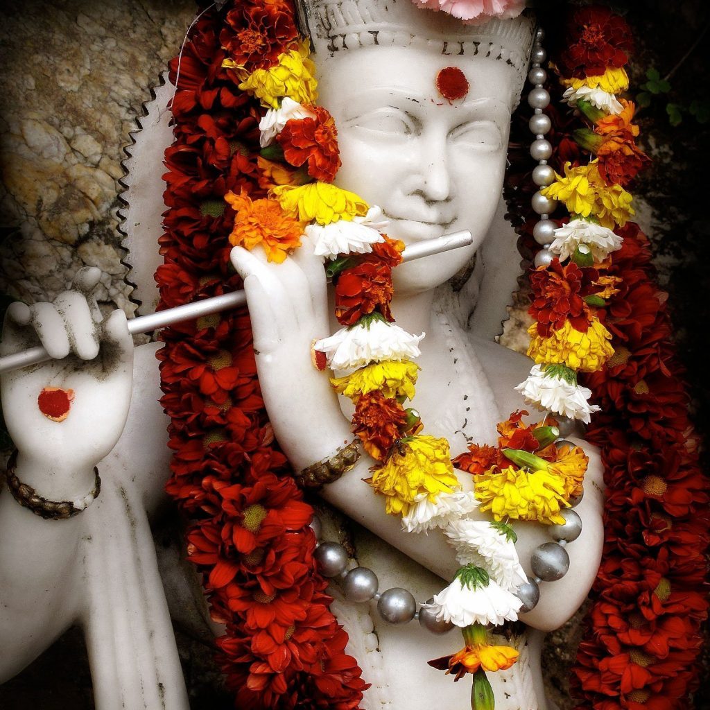 A sacred white marble murthi of Lord Sri Krishna playing the flute, with flower garlands, taken on Krishna Jayanti at Skanda Vale