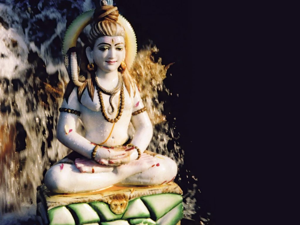 A murthi of Shiva beneath a waterfall at Skanda Vale