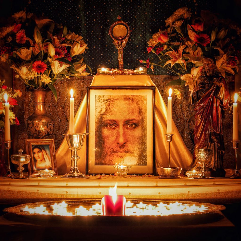 A picture of Jesus with candles on a shrine